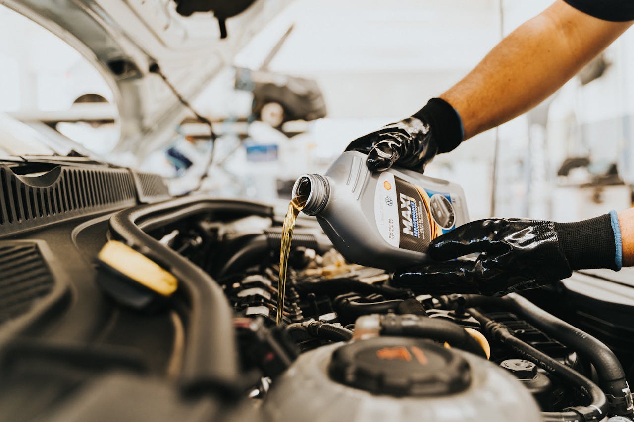 home-hero-1 Close-up of a mechanic pouring engine oil into a car engine in an auto repair shop.