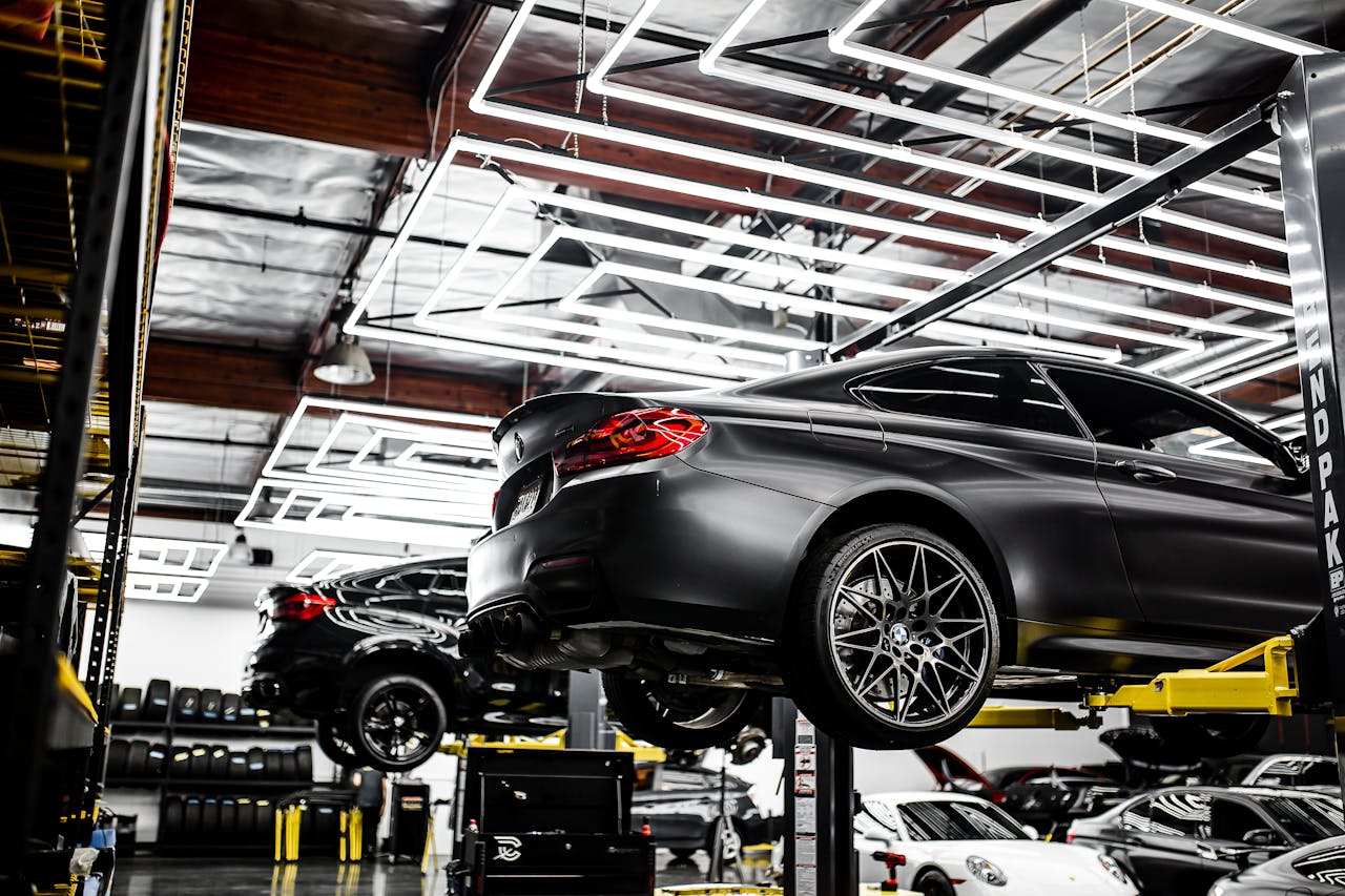 A modern car repair shop showcasing vehicles on lifts and a well-lit, organized interior.