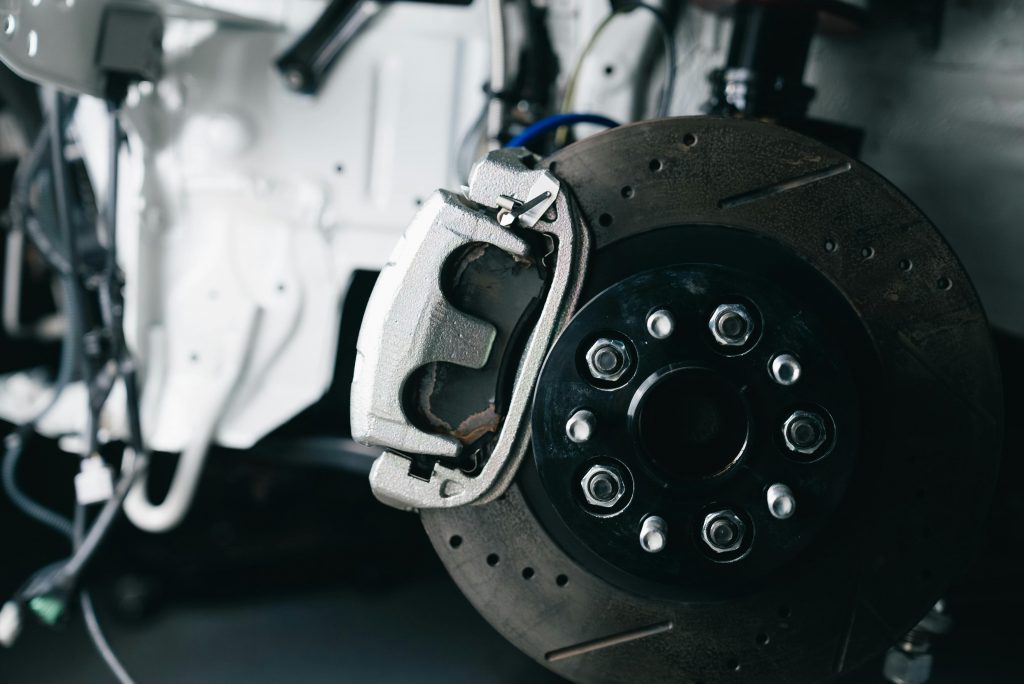 pexels photo 34277926 34277926 Detailed view of a car's brake caliper and disc in a workshop setting.